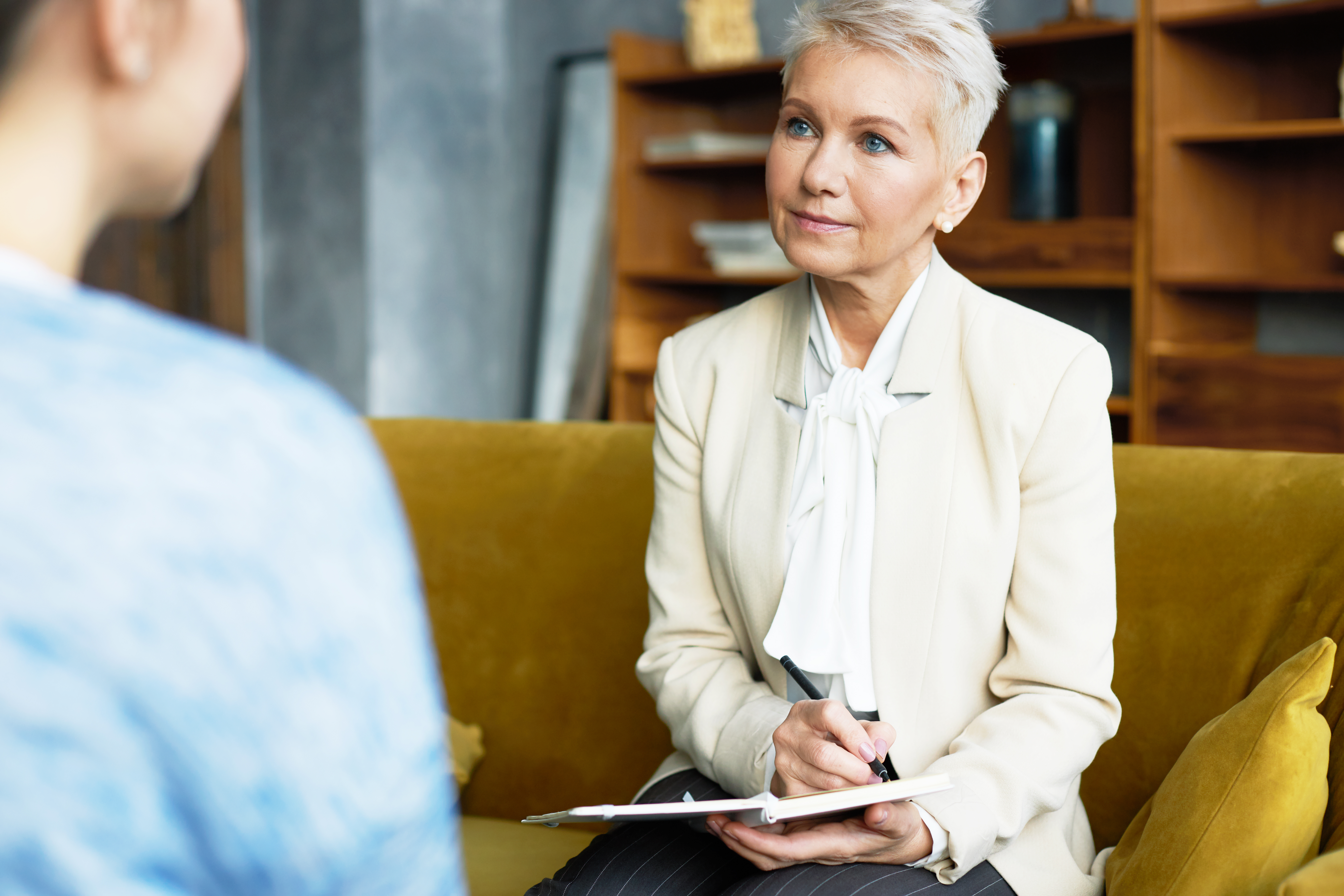 Experienced middle aged female human resources manager conducting job interview with unrecognizable woman candidate listening to her attentively and making notes. Occupation and career concept