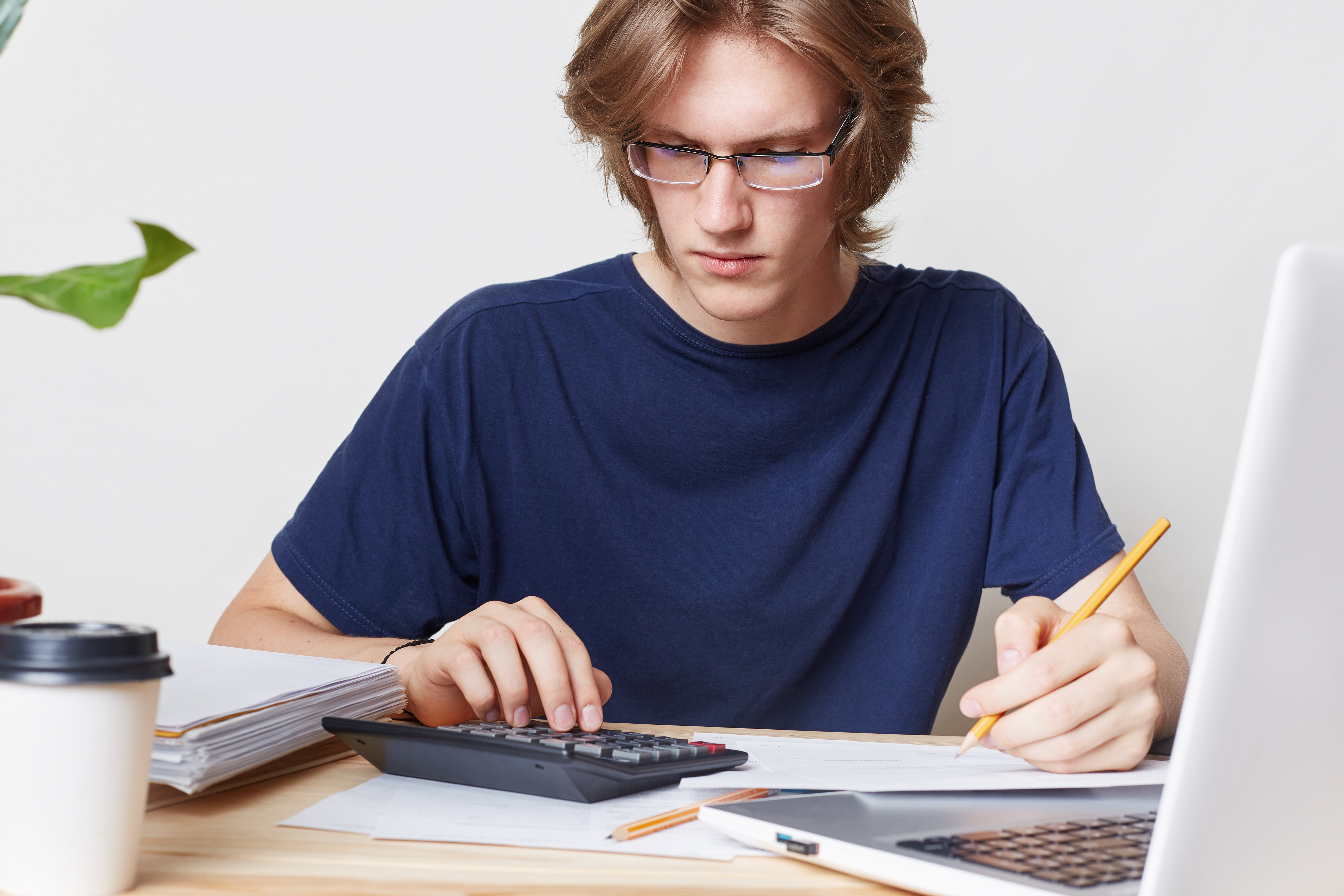 Attractive man faces financial crisis, studies notification from bank, calculates figures. Male student studies math, prepares report, calculates figures. People, business, occupation concept